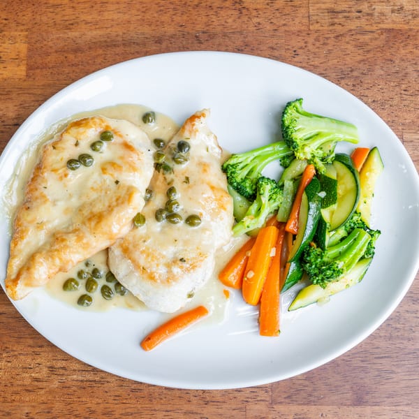Chicken piccata with capers and creamy sauce, served with steamed broccoli, carrots, and zucchini.
