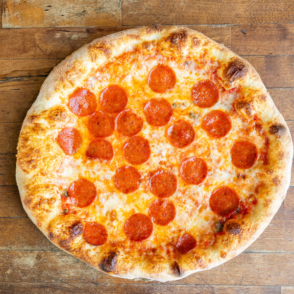 A whole pepperoni pizza with a golden crust and melted cheese on a rustic wooden table.