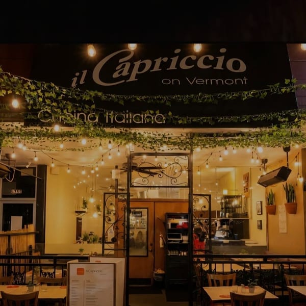 Exterior of Il Capriccio on Vermont, an Italian restaurant with illuminated patio seating and ivy.
