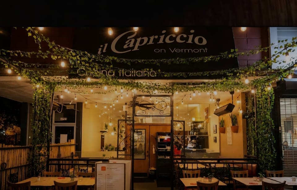 Exterior of Il Capriccio on Vermont, an Italian restaurant with illuminated patio seating and ivy.