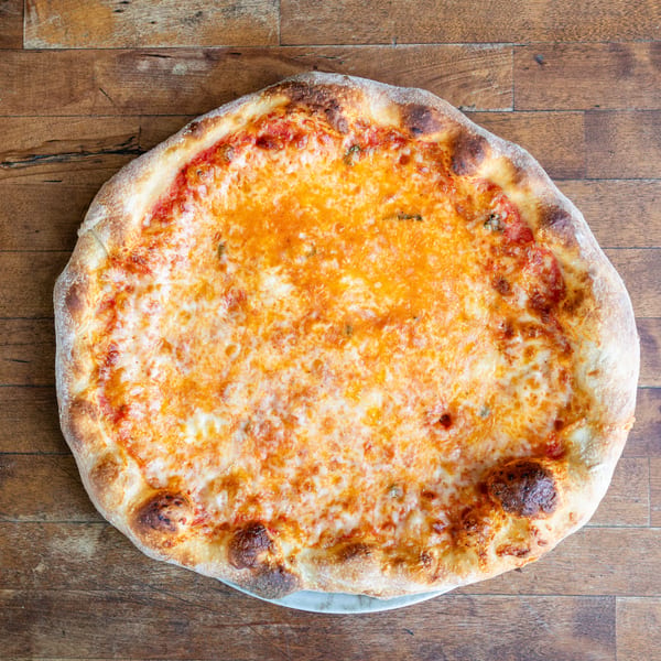 A whole cheese pizza with a golden crust sits on a rustic wooden table.